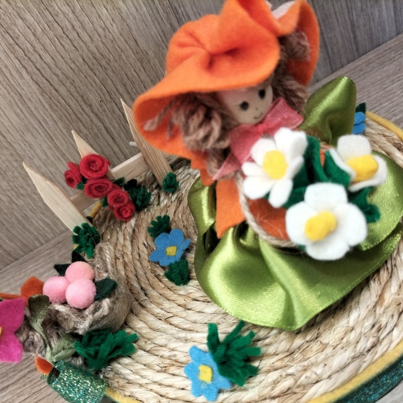 Bambolina con base e arco di fiori con fiori e steccato