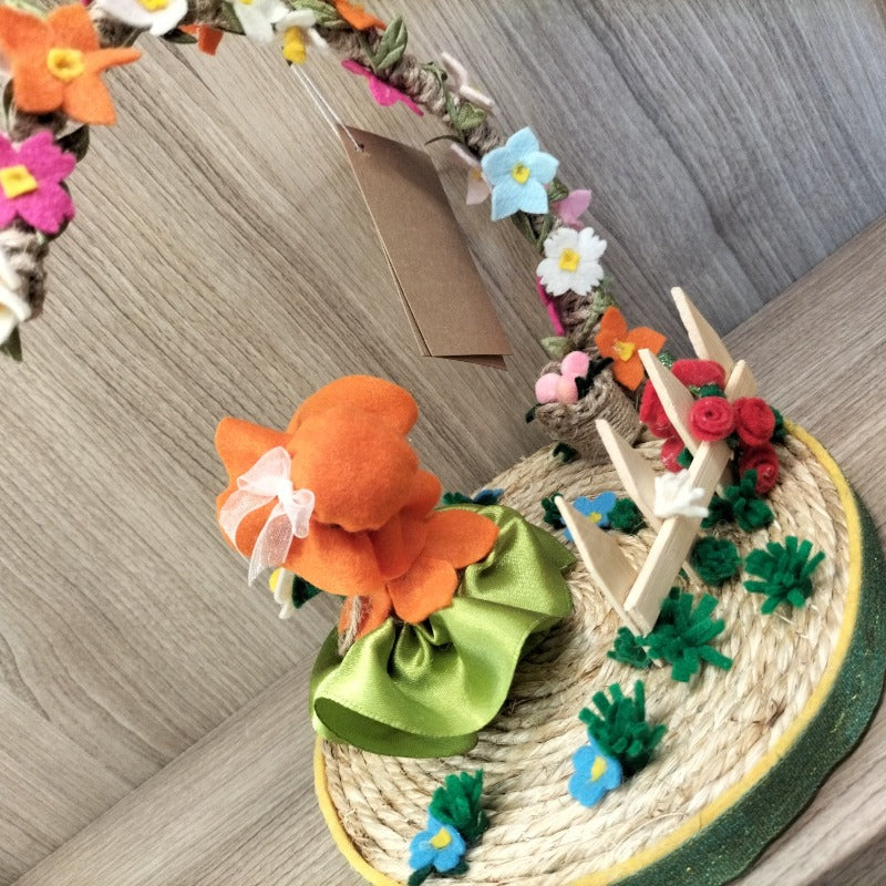 Bambolina con base e arco di fiori con fiori e steccato