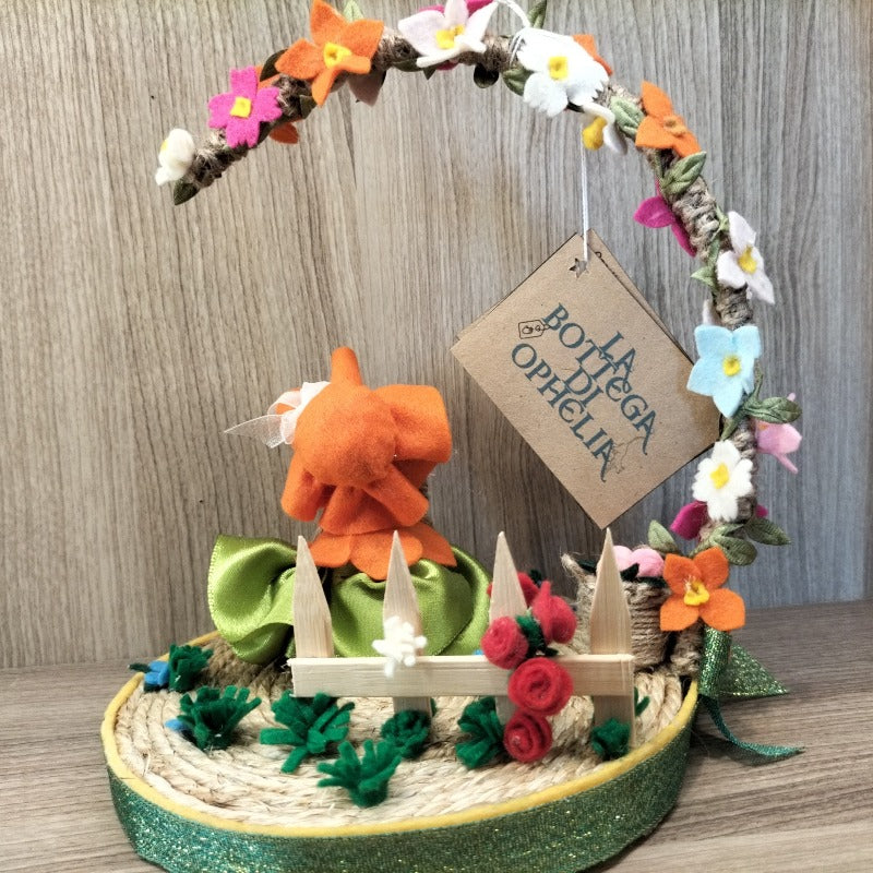 Bambolina con base e arco di fiori con fiori e steccato